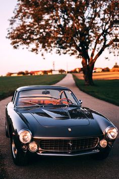 an old black sports car parked on the side of a road