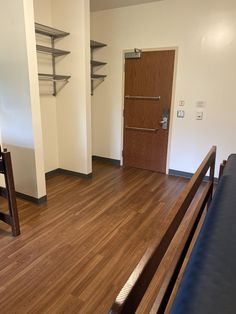 an empty room with hard wood floors and shelving