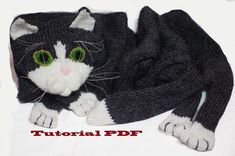 a knitted black and white cat laying on top of a blanket with green eyes