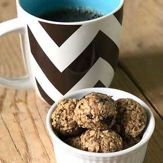 a cup of coffee and some cookies on a wooden table next to a mug filled with tea