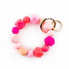 a pink, red and orange bracelet with a gold keychain hanging from it