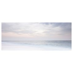 an empty beach with the ocean and sky in the backgrounnd, taken from across the water