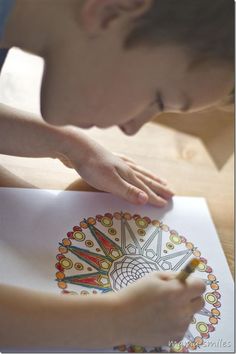 a young boy is drawing with colored pencils