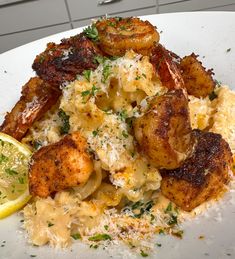 a white plate topped with pasta and shrimp next to lemon wedges on a table