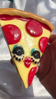 a slice of pizza has been painted to look like a clown's face and is being held by someone