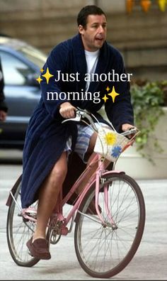 a man riding a pink bike down a street with the words just another morning written on it