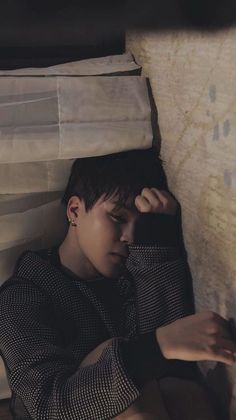 a young man laying on top of a bed next to a white sheet covered wall