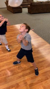 two young boys are playing with a ball on the floor in an empty room,