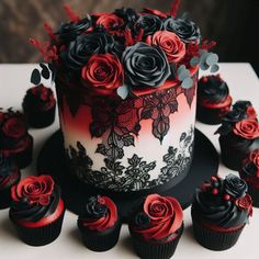 there is a cake and cupcakes on the table with red roses around it