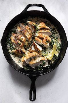 chicken and broccoli in a skillet with lemon wedges on the side