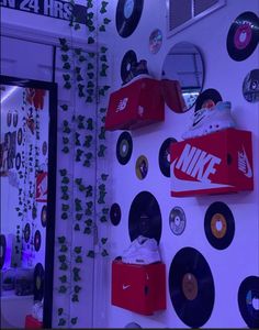 the wall is covered with various records, cds and nike shoes hanging on it's side