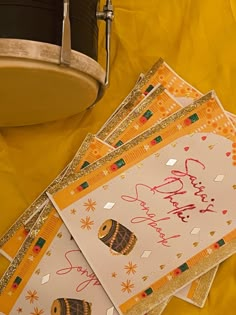 a drum and some greeting cards on a yellow table cloth with gold sequins