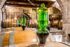 a green bottle sitting on top of a wooden barrel in a room filled with barrels