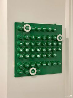 a green wall mounted calendar with numbers on it