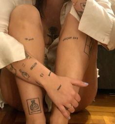 two people with tattoos on their legs sitting next to each other