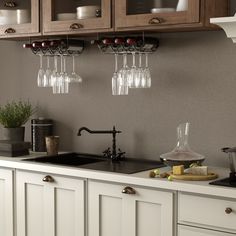 a kitchen counter with wine glasses hanging from the wall and other items on top of it