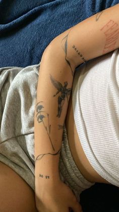 a woman laying on top of a bed with tattoos on her arm and leg behind her head