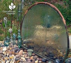 there is a mirror in the middle of some rocks and stones with plants growing out of it