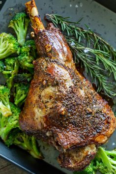 a piece of meat and some broccoli on a tray with seasoning sprigs