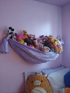 there are many stuffed animals in the hammock on the wall above the bed