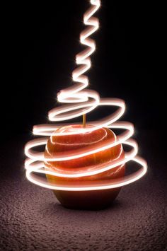 an apple sitting on top of a table next to a light painting spiral design in the dark