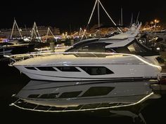 several boats are parked in the water at night time, with lights shining on them