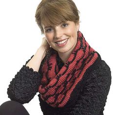 a woman wearing a black and red knitted scarf posing for the camera with her hand on her chin