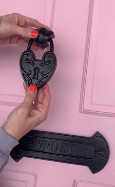 two hands are holding a heart shaped key to a pink door with the word post painted on it