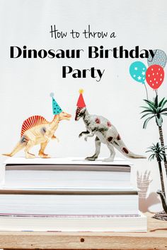 two toy dinosaurs with party hats on top of books