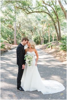 a bride and groom pose for a wedding photo in the middle of an empty road