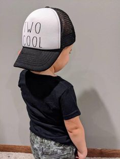 a toddler wearing a black and white hat with the words two cool on it