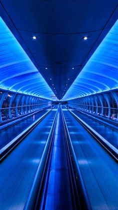 the inside of an empty subway station with blue lights on it's walls and floor