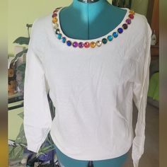 a mannequin wearing a white shirt with multicolored beads on the neck