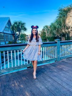 a woman standing on top of a wooden deck wearing a minnie mouse ears headband