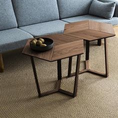 two tables sitting next to each other on top of a carpeted floor in front of a blue couch