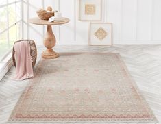 a white rug with pink and beige designs on the floor in front of a window