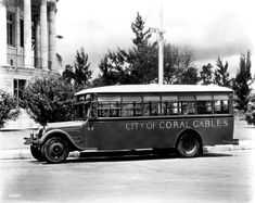 an old city bus is parked in front of a building with columns on the side