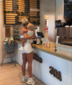 two women standing at a counter in front of a coffee shop with their arms around each other