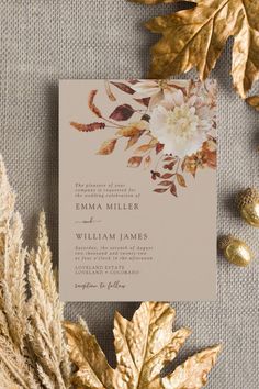 the wedding stationery is surrounded by autumn leaves and gold foiled foliage, which matches the neutral color scheme