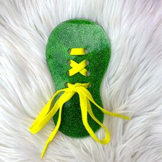 a green mask with yellow ribbons on it sitting on white fluffy fur covered flooring