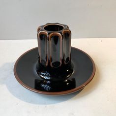 a black and brown vase sitting on top of a saucer in the middle of a plate