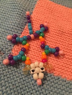 the beaded necklace is laying on top of the knitted blanket with beads and charms