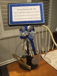 a musical instrument on top of a wooden chair with a blue ribbon and music notes attached to it