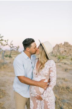 a pregnant couple kissing in the desert