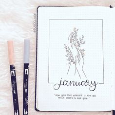 an open notebook with the words january written on it and two pens next to it