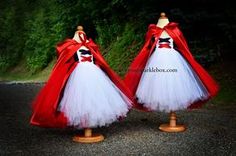 two red and white dresses with capes on stands in the middle of a road