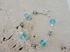 "Light Aqua 10mm Czech rondelles remind you of the ocean in this silver plated wired bracelet.   German wire was used to link the alternating Czech beads and silver plated round metal beads.   The clasp is a sterling silver toggle clasp.  Size 7 1/2 \"  To view more items in my shop please click the link below:   https://www.etsy.com/shop/CopperTulipDesigns?ref=hdr_shop_menu  To view other bracelets in my shop, please click the link below: https://www.etsy.com/shop/CopperTulipDesigns?section_id= Silver Spacer Beads Jewelry For Beach, Silver Bracelets With Lobster Clasp And Czech Glass, Wired Bracelet, Teal Bracelet, Nautical Bracelet, Beach Bracelet, Beach Bracelets, Free Bracelet, Light Aqua