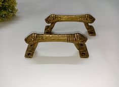 two gold colored handles on white surface with flowers in the background