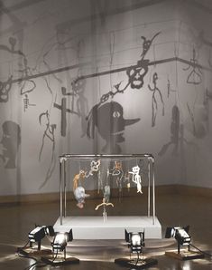 an exhibit with various objects on display in front of a shadow projected wall behind it