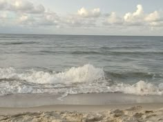 an ocean view with waves crashing on the shore and clouds in the sky over the water